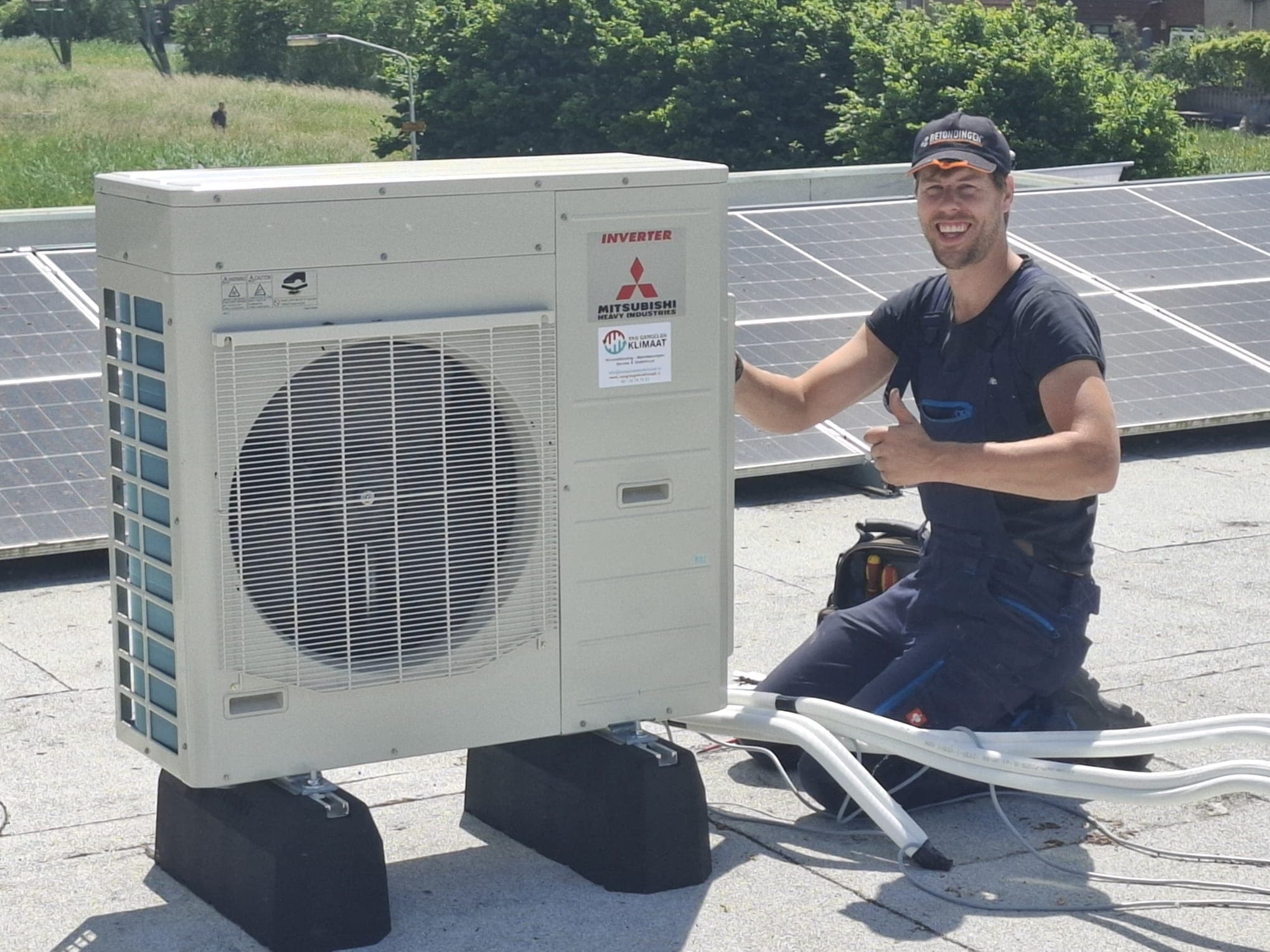 Monteur geeft duim omhoog naast geïnstalleerde Mitsubishi buitenunit